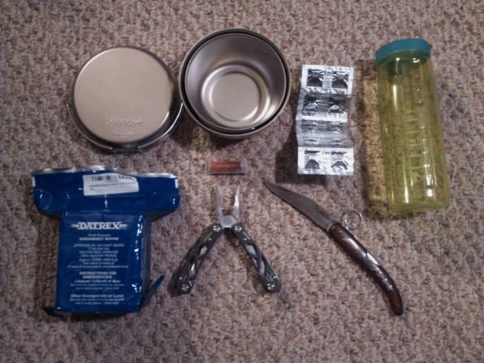 From left to right: steel pot and pan, water purification tablets, container, rations, multi tool and flip knife.