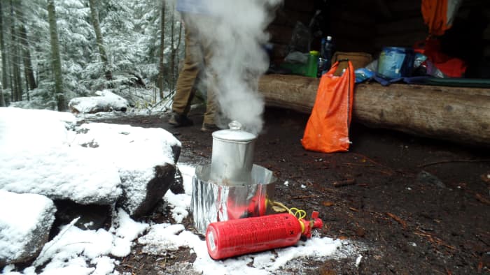 Hacer café con un percolador en una estufa de campamento. 