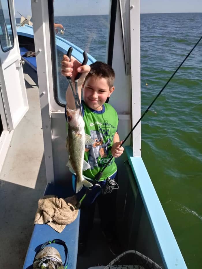 A young man hoisting his prized catch, spring is the perfect time to take children as the schools are dense and even a novice can land a few fish quite easily.