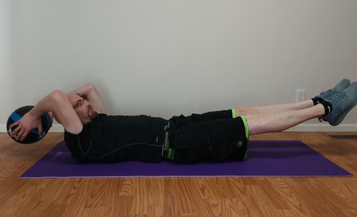 To do a full extension with a medicine ball, bring your knees up to your chest and the medicine ball up to your knees