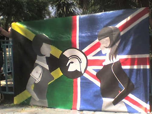 This is a Jamaican and British flag with the Trojan Records helmet uniting them. On the flag, white and black skinhead girls stand across from each other.