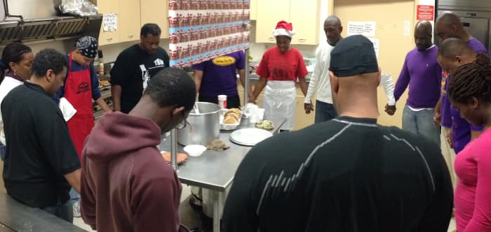 Volunteers pause for prayer in the kitchen before serving breakfast at the Kwanzaa Kitchen.