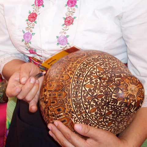 Demonstration of Peruvian gourd burning. Note the burning charcoal in her right hand.