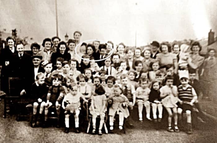 Street party to celebrate victory in Europe in May 1945. Mum is pictured holding a neighbour's toddler and standing next to her brother, Kenneth (circled in the photo, to the left of the centre at the back).