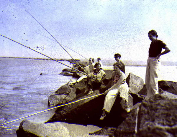 Young women fishing with cane poles from a jetty.