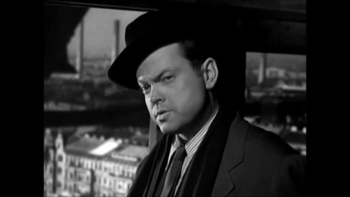 "He-e-ere's Harry!" Orson Welles discusses the finer points of his business with friend Joseph, "Butt out!" is the essence of his message.