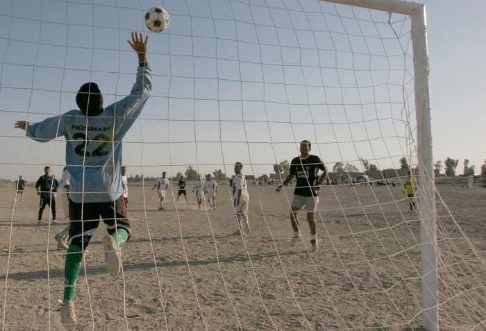 A goalkeeper jumping up to block an attempt at scoring.