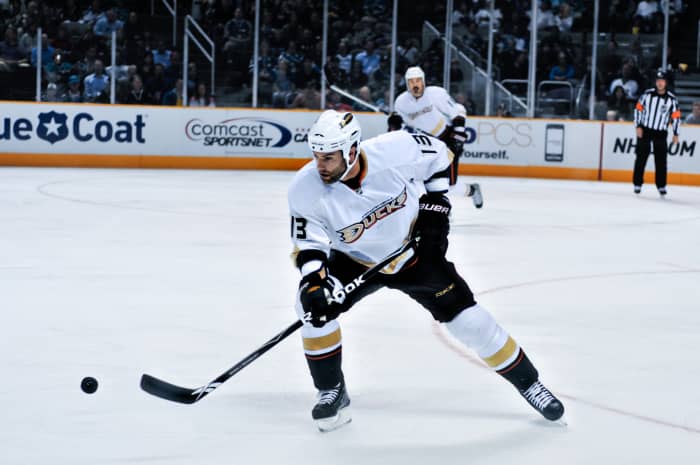 A hockey player is skating on ice while holding a hockey stick. He is going for the puck.