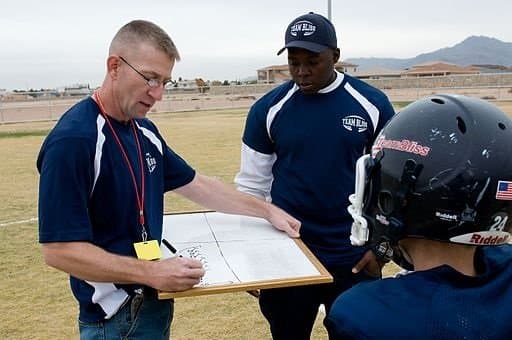 El Paso Texas Team Bliss Head Coach Kenneth Gipe (left), writes up a new play prior to a game.