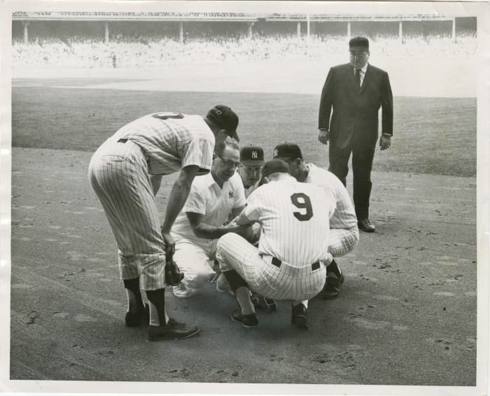 3rd inning, Game 2: Roger Maris is being checked out by the trainer and Houk. Joe Pepitone and umpire John Rice look on.