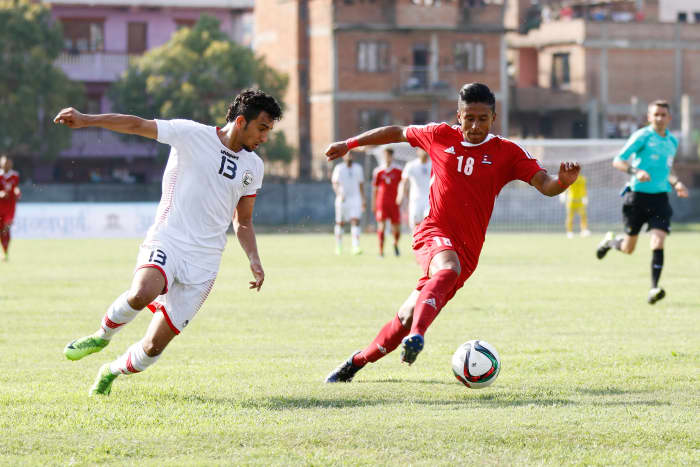 A Yemeni player (white) and a Nepali player (red) battle for possession of the ball during a 2019 Asian Cup third round qualifier on June 2017 at Halchowk Stadium in Kathmandu, Nepal.