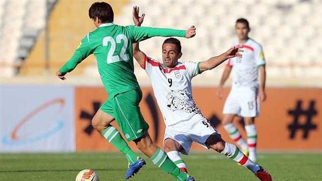 Seldar Geldiyev of Turkmenistan (22, green) attempts to evade a tackle from Omid Ebrahimi (9, white) during a 2018 FIFA World Cup qualifier on November 12, 2015 in Tehran, Iran. The match, played at Azadi Stadium, ended 3-1 to Iran.