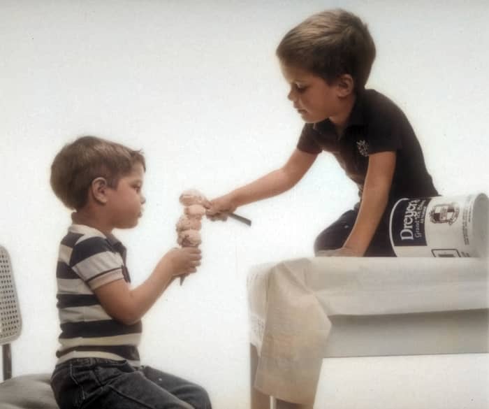 The artificial intelligence did a pretty good job with this photo, but I would make the stripes on the boy's shirt red and the tablecloth yellow.