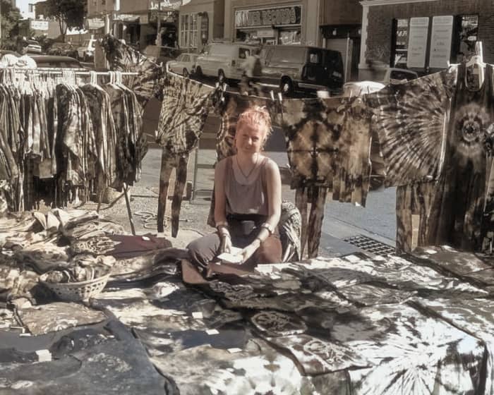 The AI had no idea what color to make this vendor's colorful tie-dyed apparel, so it gave up entirely.