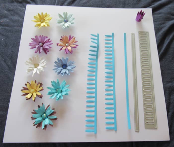 Dies are easy to use for rolled flowers. You use a die machine to cut the die, Then you roll and glue the flowers together. Showing the die and the die cut. Upper right hand corner shows the flower after it is rolled, Then the final flower design/
