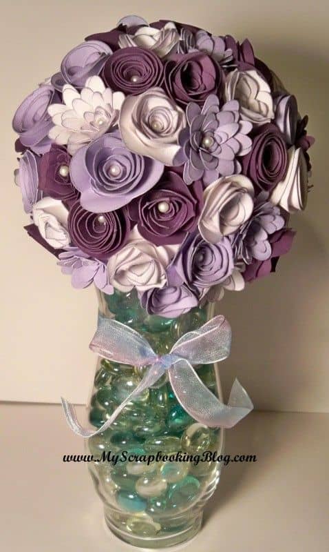 You can take a rolled flower and make an arrangement for your home or as a gift. Simply bend a floral wire and hot glue the flower to the stem. Wrap it in floral wire, Add paper or silk leaves. Arrange in a vase or a container.