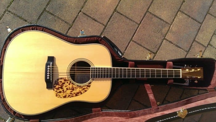 The Martin D-28CW, large sound hole, solid black ebony fingerboard, and dalmatian pickguard are the visual hallmarks.