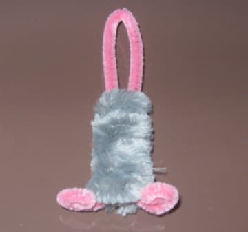 3. Insert the bent pink pipe cleaner through the center of they grey coil. It should stop at the small spirals - lightly pinch and bend the spirals underneath the coil to form the mouses feet.