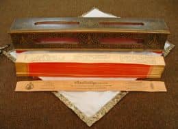 In ancient times the Pali Canon was written on thin slices of wood. The 'pages' are kept on top of each other by two thin sticks, which go through little holes in the scripture. The scripture is wrapped in cloth and stored inside the box