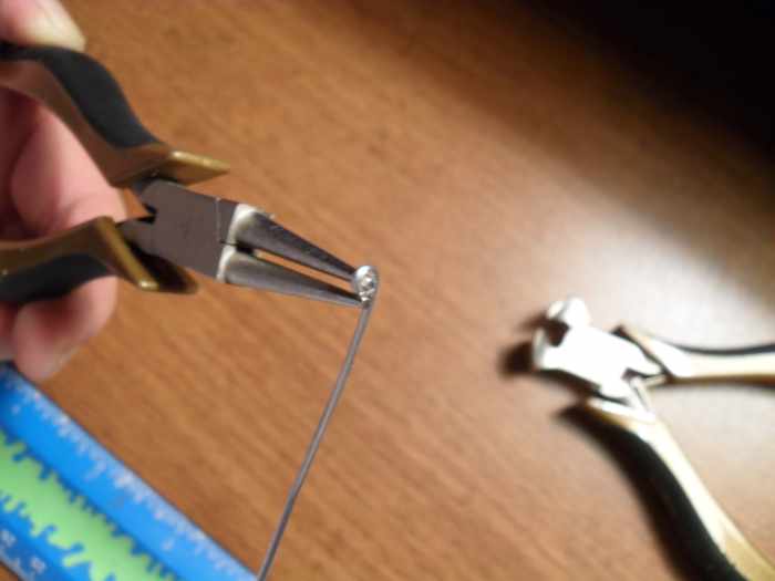 Take the length of silver wire and form a closed end loop on one end. This will form 1/2 of the an eye on the clasp end used for attaching the clasp to the silver chain.