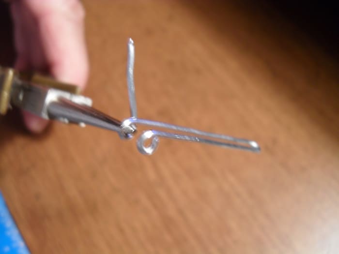 Form the second eye just like you did the first one.Wrap the tag end around the chain nose pliers to form the second eye. They should lay side by side with the holes lined up.