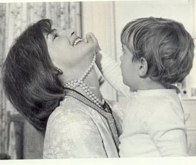 photo of Jackie Kennedy wearing her famous three strand pearl necklace with JFK Jr playing with the necklace