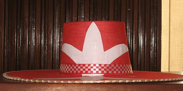 Eyo Laba Hat - A red hat with a white emblem and a chequered band, worn by the Eyo Laba masquerades.