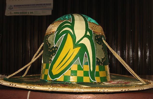 Eyo Ologede Hat - This group's very stylish hat has an elaborate emblem of a banana and a chequered green and yellow band. (Ogede is banana in Yoruba language)