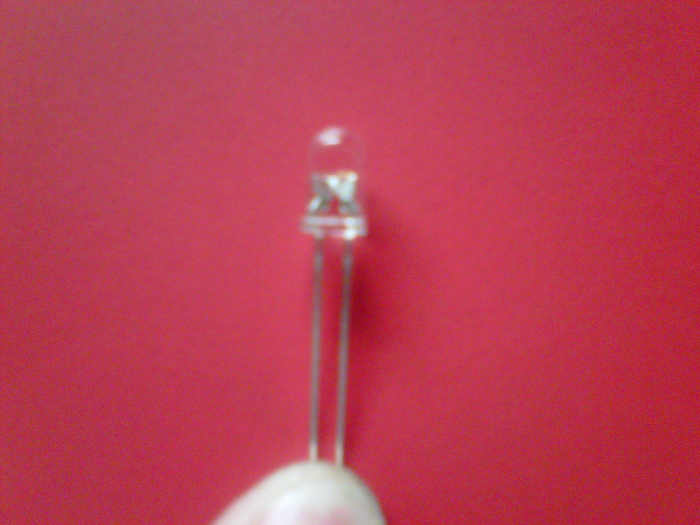 In addition to the positive leg being longer, it's also got the smaller part of the element attached inside the plastic.