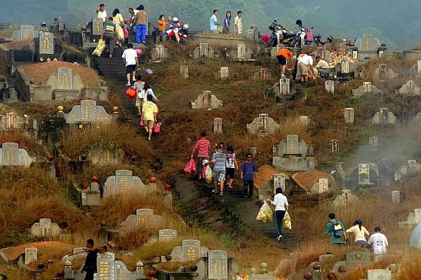 Typical scene during Qingming festival with family members bringing offerings for prayer, cleaning and tending to the graves.