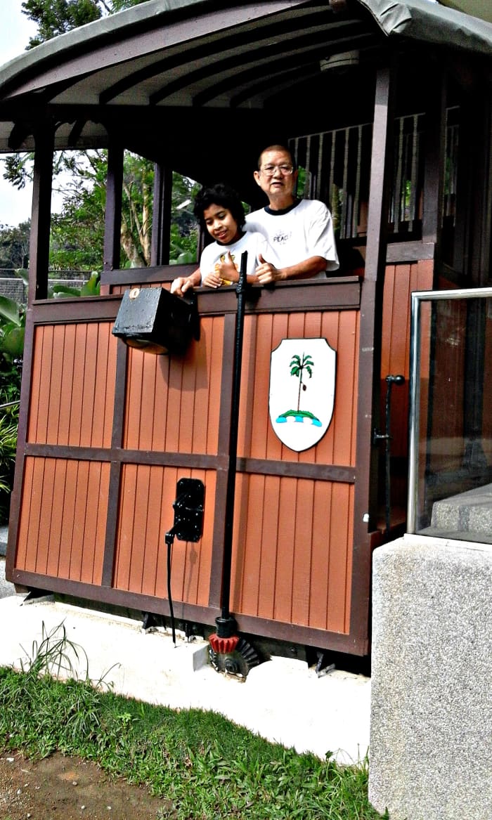 Nostalgic encounter. Author Good Guy with granddaughter standing inside the old timber coach on display at the top of Penang Hill. The exact coach he used to travel in, 41 years ago!