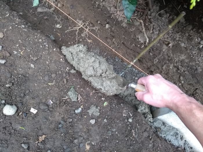 Use a shovel, spade or builder's trowel to lay a bed of concrete for several stones.