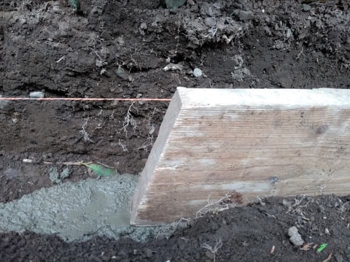 Using a piece of board or similar as a guide, the same height as a stone, check the bed is deep enough so that stones can be hammered down about 1/2 to 1" (12 mm to 25 mm) into it.