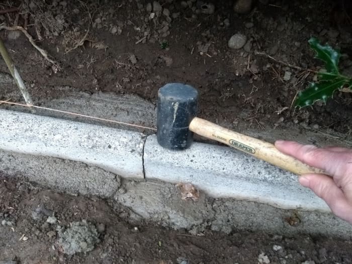 Use a mallet or the handle of a lump hammer to tap stones down into the bed. Don't use the hammer head itself to avoid chipping or cracking concrete. (Sorry this photo is out of sequence taken after haunching added at the front!)