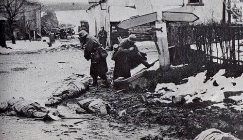 German soldiers stealing dead GI's boots in the village of Honsfeld. The road signs have been blocked out by the censors.
