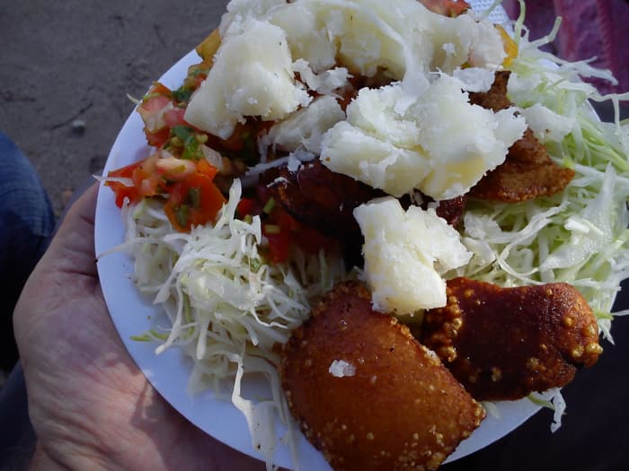 A plate of vigorón, pork skin fried in pig lard with boiled yucca root, shredded cabbage and chimichurri.