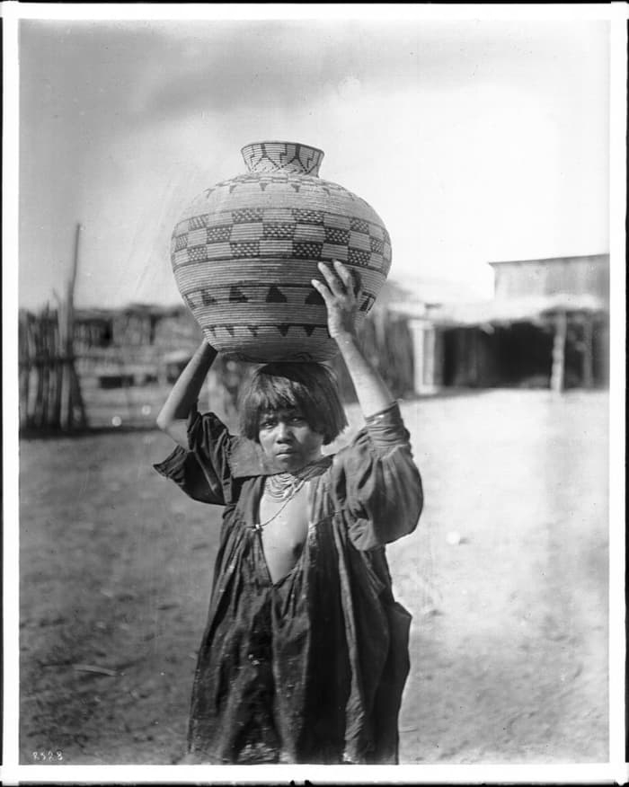 Apache Indian girl carrying an olla (a water basket) on her head, ca.1900. Photo by Charles C. Pierce.