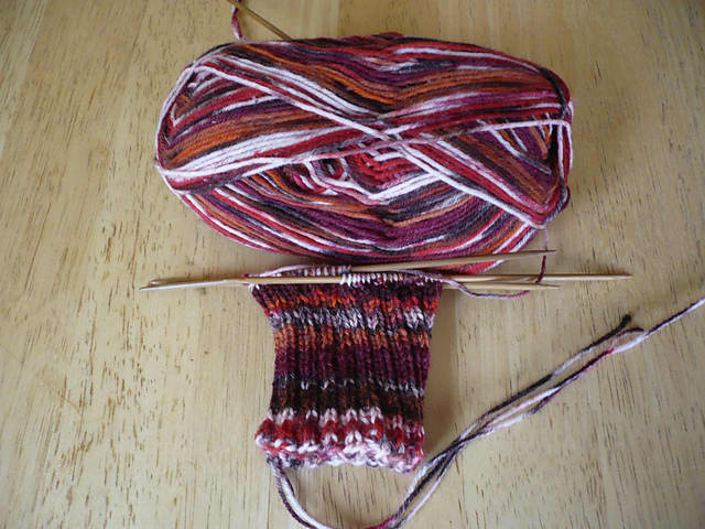 Work in Progress (WIP) - a knitted sock partially done on Double Pointed Needles (DPNs) using variegated sock yarn.