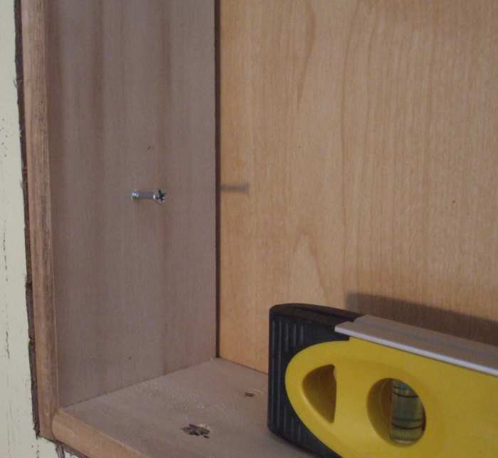 The screw was started in the side of the box, but no pilot hole was made in the stud until the level gave its approval.