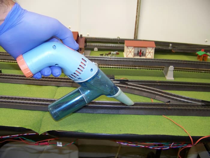 I purchased my Darice brand hand-vacuum from a local craft store, it uses four AA batteries and has just enough vacuum power to pick up loose dirt.