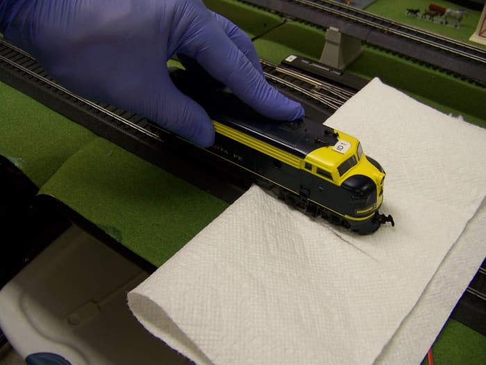Cleaning the powered wheels of the locomotive can be achieved by turning on track power and touching the non-powered wheels to the track while the powered wheels rub against a paper towel.
