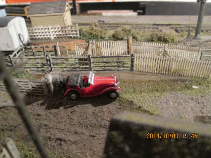 A snazzy looking sports car stands beside the livestock dock. View looking over the smithy roof