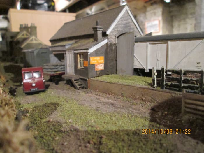An older railway-owned 'mechanical horse' has released its flatbed trailer in the doorway of the goods warehouse - a fish van stands outside awaiting unloading by local fish merchant or collection by next pick-up goods train