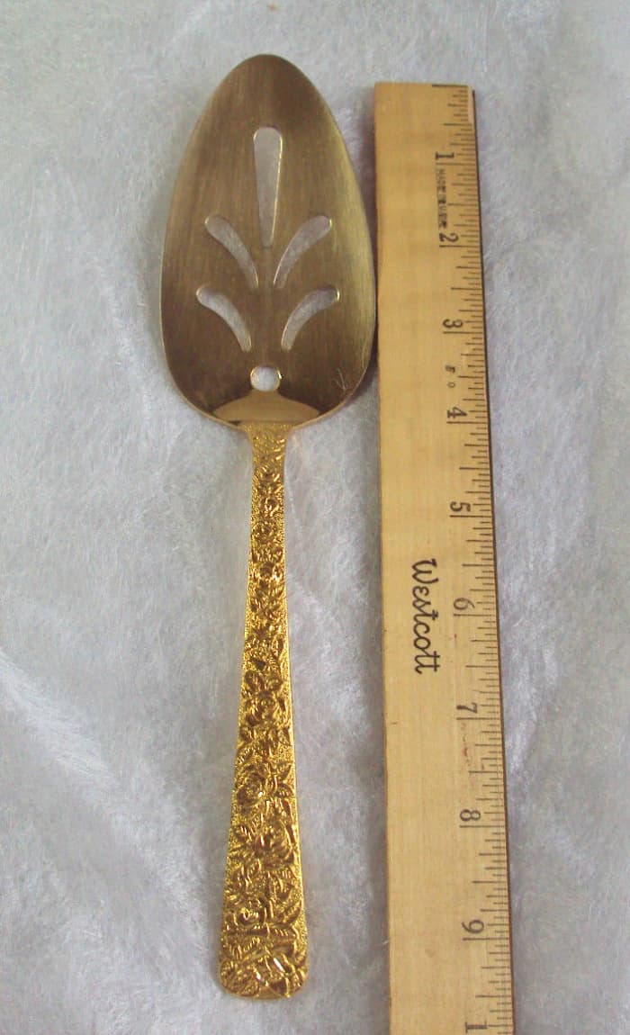 A gold platted rose patterned serving spoon flatware by Cellini Romanesque of New York and made in 1968.It has a glossy finish and it is 9-1/2 inches long. This is a beautiful piece perfect for any festive holiday or celebration table.