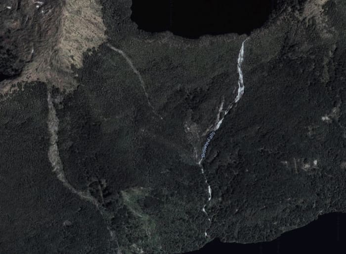 Browne Falls is located on a steep cliff coming down from a lake above. The falls can be seen in the picture as the white streak coming down from Browne Lake at the top of the picture.