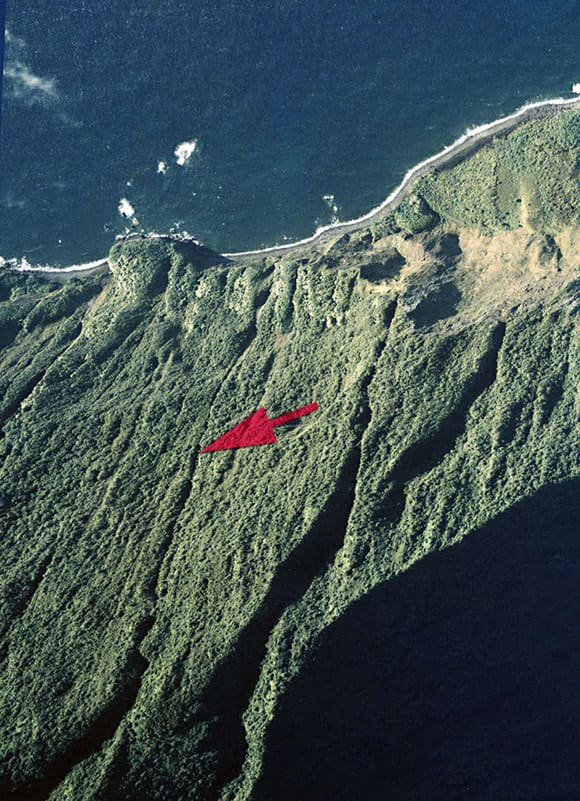 Pu'uka'oku Falls is seen here pointed out by the large red arrow marker. The falls are very narrow and are hidden nearly completely by the brush on the side of the seaside cliff.