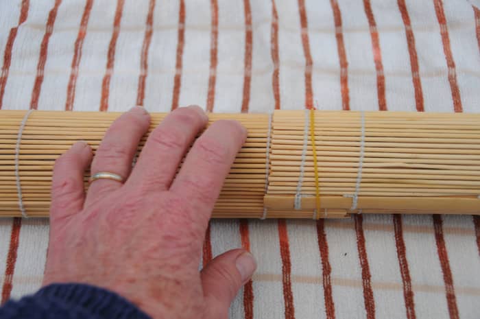 Rolling on a tea towel helps to soak up any additional moisture and makes it easier to roll the sushi mats.