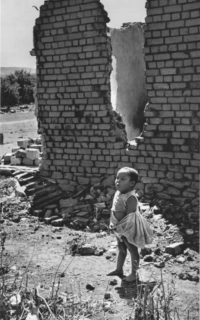 A child stands next to her home which was bulldozed through 'forced removals' of Africans from places the Apartheid regime dubbed "Black Spots"