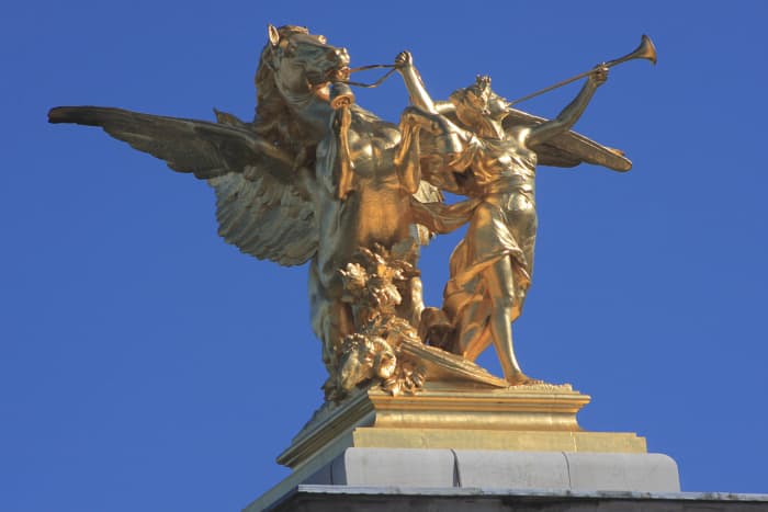 This gilded statue on a 17m (56 ft) high granite plinth, is one of four which guards the entrances to the Pont Alexander III Bridge. The bridge spans the River Seine between the Grand Palais on the north (left) bank, and Les Invalides to the south