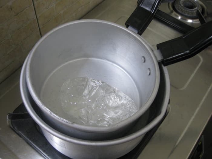 Place the smaller saucepan with the jelly-like gel wax drizzled with fragrance oil on top of the boiling water in the bigger saucepan.